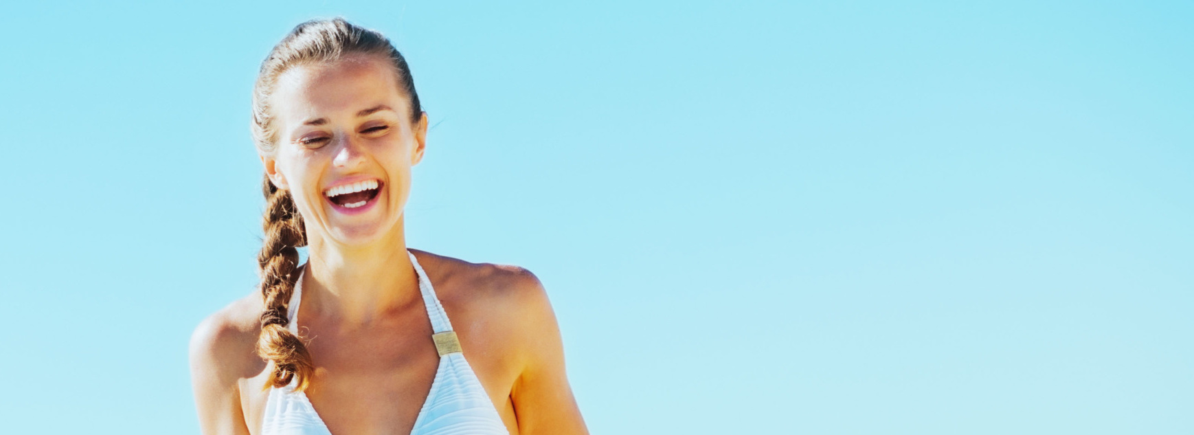 Jeune femme souriante marchant au bord de la mer.